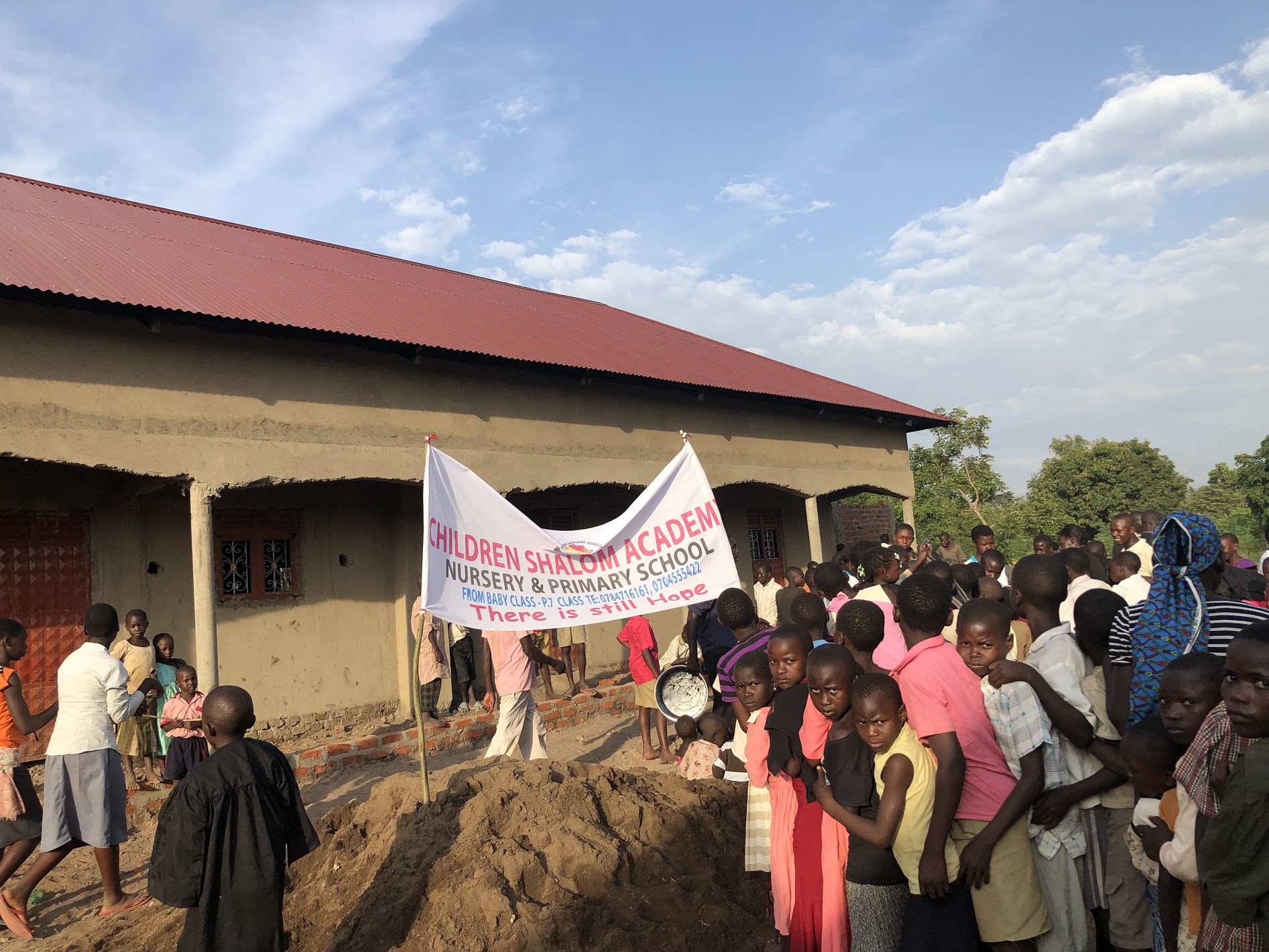 Sign in front of the school building with a crowd of mostly-children